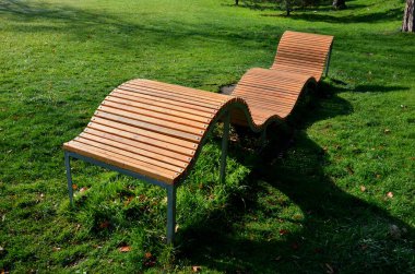 design bench in the shape of a wavy line. wooden paneling on a metal galvanized frame. The bench is atypical to order in a city park for young people and unusual sitting and lying