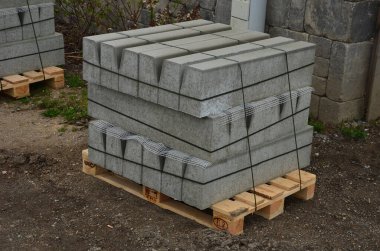 Kaldırım ve kaldırım yenileme için kaldırımlı paletler hazır. İnşaatçılar çimento fabrikasındaki ucuz gri beton ürünleri kullanıyorlar. Yolu ve kaldırımı ayırır.