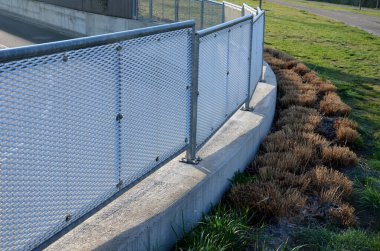 Genişletilmiş metal levha eskrimi. Galvanize parmaklıklardan yapılmış çok dayanıklı parmaklıklar. Süslü otların şeridi mekana insafsız bir bakış kazandırıyor. Öğütücü olarak yarı saydam