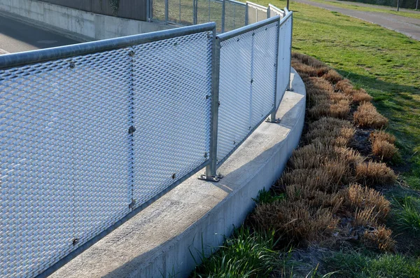 Genişletilmiş metal levha eskrimi. Galvanize parmaklıklardan yapılmış çok dayanıklı parmaklıklar. Süslü otların şeridi mekana insafsız bir bakış kazandırıyor. Öğütücü olarak yarı saydam