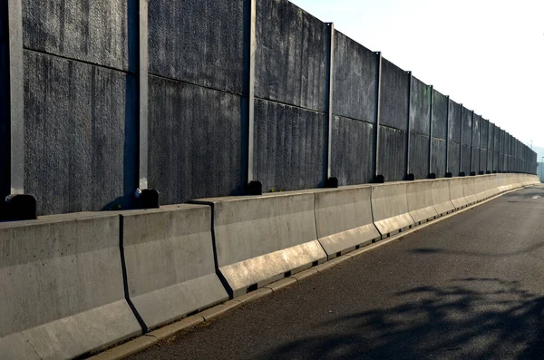 soundproof wall made of concrete porous ribbed material. fence of gray blocks embedded in metal beams, on street. road traffic noise  garden and residential area. protection of Jerusalem, rocket