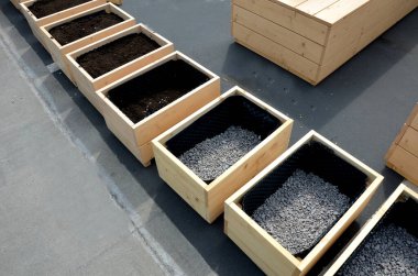 preparation for planting flower pots. wooden flower pots are filled at the bottom with gravel as drainage. the sides are covered with black foil with bubbles