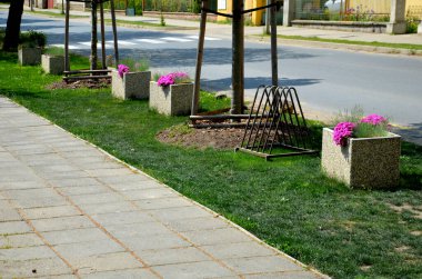 Terastaki park yerinde iki gri saksı ve bir çimenliği andıran yapay bir şey. Bir tencerede graslar ve mor çiçekler var. Restoranın yanındaki spa parkı.