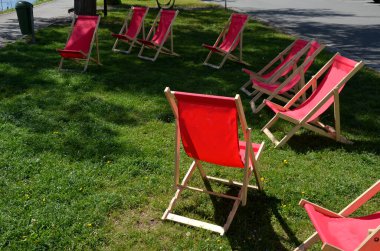Nehrin kıyısındaki restoranın önündeki çimenlikte yaya olarak duran katlanabilir ahşap hamak sandalyeleri. Bisiklet yolu bisikletçileri soğuk içeceklere ve dinlenmeye götürüyor. güneşlenen kız