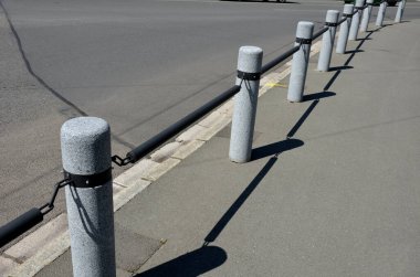 Kaldırımın kenarında zincir gibi asılı çubuklarla birbirine bağlanmış granit sütunlar var. Silindirik sütunlar yayaları araçlardan korur. taş ürünleri