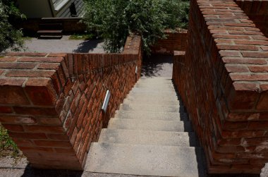 Merdivenler ve açık tuğla parmaklıklar pürüzsüz yüzey. U şeklindeki tuğla istinat duvarlarının köşelerindeki metal korkuluklar ve banklar. Aralıklı ışıklar yayaların ayaklarının altını aydınlatıyor.