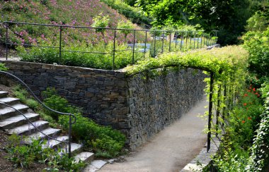 Yokuş aşağı kestirme yol. Yolun üstünde ve altında taş bir duvar var. Sonbahar parkında kanalizasyon ve metal şebeke ile doğa izleri. Her yer kuraklıkla kaplıydı. Her yıl sarı, porsuk, kaya...