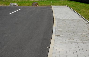 Park yerlerinden korunmak için şeritler arasında gri taşlar var. Taşımacılık çözümleri şehir yolu ve bisiklet yolunun yanındaki otoparkta. asfalt yüzeyler ve çimenler