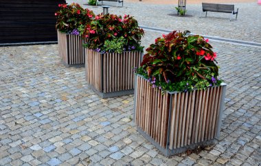 ornamental flower pots on village center trough, wooden flower pots with beautiful decorations of violets and daffodils. Easter is approaching so it is necessary to decorate entrance of home, parking