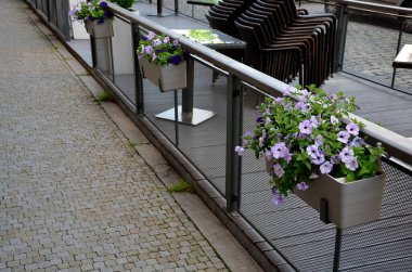 Teraslı bir evin penceresinde süslü saksılar. Menekşeler ve nergislerle süslenmiş plastik saksılar. Paskalya yaklaşıyor, bu yüzden giriş terasını süslemek gerekiyor.