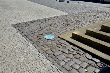 Meydandaki üç sıra merdiven kademeli olarak kaldırıma gömüldü. Binanın girişinde granit ve mermeri karıştırarak, birleştirerek ve kesiştirerek merdivenlerin düzleme yavaş geçişi
