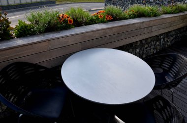 Balkondaki terasın korkulukları doğal teras tahtalarının oluşturduğu oyuk profilli kutulardan oluşuyor. Masa ve sokak arasındaki arayüz çiçekli otlardan oluşur.