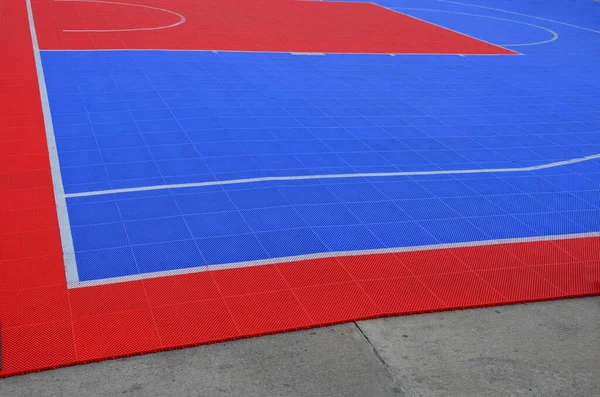 A volleyball court was created in the parking lot. the tiles connected and portable form a red-blue plastic platform on the concrete floor. mattress, plastic grid, rubber, soft