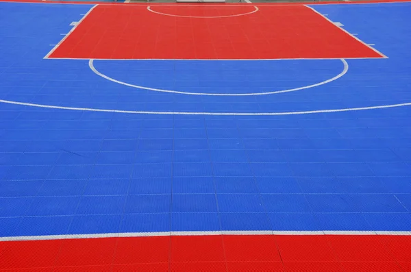 A volleyball court was created in the parking lot. the tiles connected and portable form a red-blue plastic platform on the concrete floor. mattress, plastic grid, rubber, soft