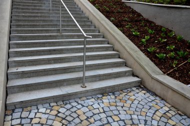 new plantings of perennials in the sloping park with anti-erosion battening. retaining walls cast from concrete in graceful arches. staircase with central railing metal steel, silver
