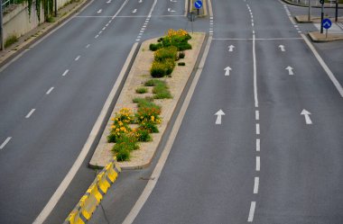 Trafik işaretleri için yatay çizgiler. Yolda beton bariyerler var. Araç şeridi ayırıcısı. Siyah çizgili sarı renk. Karayolu şeritleri arasında mavi uzun ömürlü çiçek tarhı