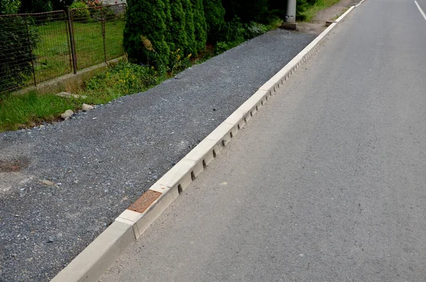 drainage hidden on the edge of an asphalt road Drainage system hidden in a perforated concrete gray curb. the water along the entire length of the road drains into the sewer through holes