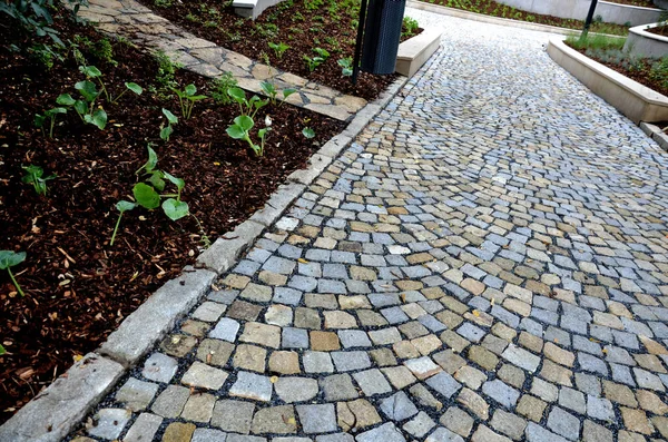 new plantings of perennials in the sloping park with anti-erosion battening. retaining walls cast from concrete in graceful arches. staircase with central railing metal steel, silver