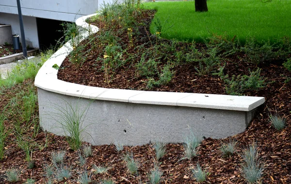 new plantings of perennials in the sloping park with anti-erosion battening. retaining walls cast from concrete in graceful arches. staircase with central railing metal steel, silver