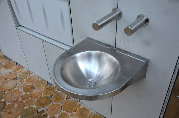 stainless steel sink with automatic battery reminds the interior of an airplane. however, it is on the bike path by the public toilets. There is also a changing table for babies, folded out