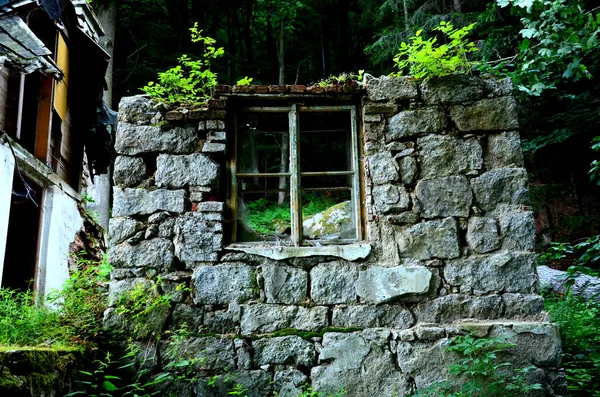 a window in the stone wall of the ruins of a mountain house damaged by an earthquake and a landslide in the mountains. a hut destroyed and abandoned in the forest