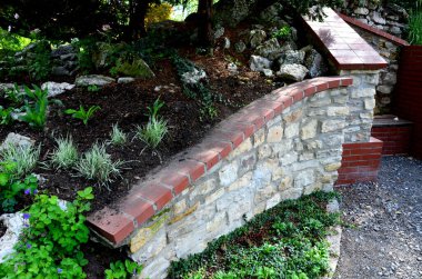rugged backyard with brick walls and flower pots. alcoves for benches and a sink in the park behind the fence. garden terrace with stone, pumice stone, sedum plant, 