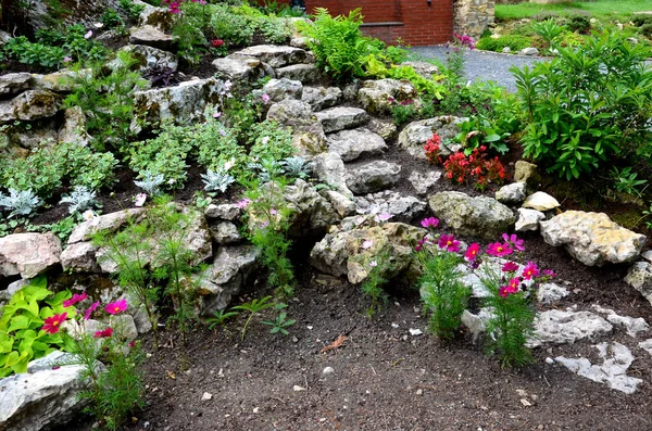 bright limestone staircase on a rock in the garden. steps of rough stones to a hill with flowers. pink red flowers around the path. karst scenery in a historic corner in a romantic park