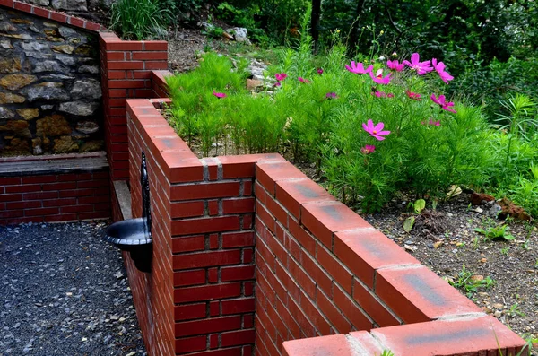 rugged backyard with brick walls and flower pots. alcoves for benches and a sink in the park behind the fence. garden terrace with stone, pumice stone, sedum plant,