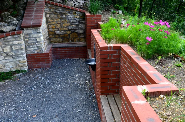 rugged backyard with brick walls and flower pots. alcoves for benches and a sink in the park behind the fence. garden terrace with stone, pumice stone, sedum plant,