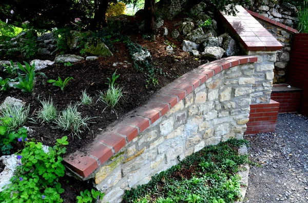 rugged backyard with brick walls and flower pots. alcoves for benches and a sink in the park behind the fence. garden terrace with stone, pumice stone, sedum plant,