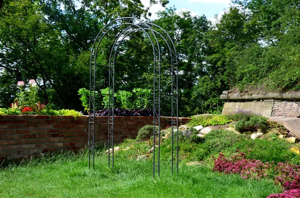 decorative garden behind the wall, with a wooden table and decorative trellis for climbing plants or for garden wedding ceremonies, rock garden with stairs, limestone