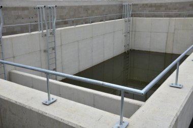 sludge, retention sump, concrete tank divided by a partition. two control galvanized metal ladders lead into the water. rainwater is purified and sedimented here. sewage and drainage water treatment 