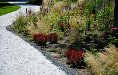 beds of newly planted flowers are planted and mulched with bark. bluebells and cypresses, paths strewn with marble dust twist through the park. supporting granite gabion basket wall, blooming, edge clipart