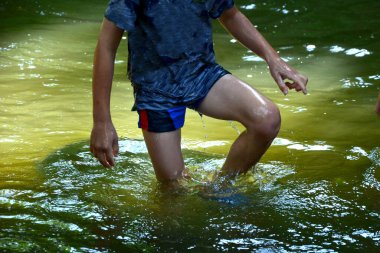 The boys sail on a boat made of old tin, tubs, a bucket, a barrel, a bowl, an oval-shaped flower pot. they fall on the river with their hands. they are children's adventures in the village