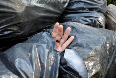 dead man in a black plastic garbage bag. bags for the dead from which a man's hand peeks out. public waste dump, on-site criminal police investigation. kidnapping, torso mutilated
