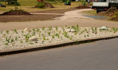 Süslü çiçek tarhı. Gri granitten yapılmış taşlar, şehir bahçesinde saman taşları, çayırlar, süs otları, havuzun kenarında çimenlik çakıl taşları.
