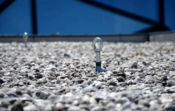 gravel mulch on the roof of a flat green roof. covers and protects layers of insulation and has a decorative effect. handle, staple, eyelet for tying the climbing rope and clips for safe work