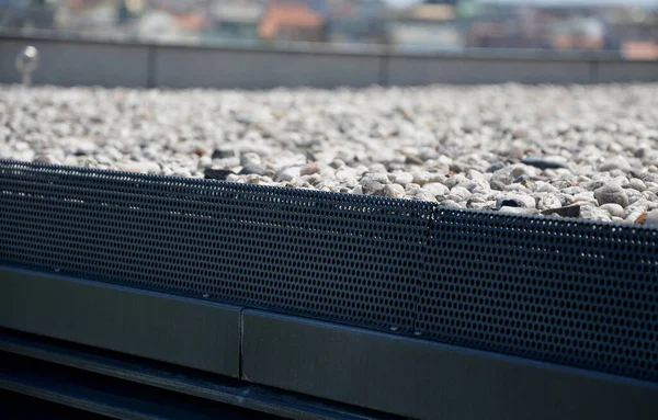 gravel mulch on the roof of a flat green roof. covers and protects layers of insulation and has a decorative effect. handle, staple, eyelet for tying the climbing rope and clips for safe work