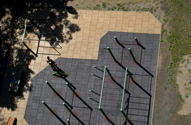 a view from a drone, from above, of a sports field equipped with several bars and benches for the gym. the surface is made of soft rubber that wipes the joints from impacts. park, lawn