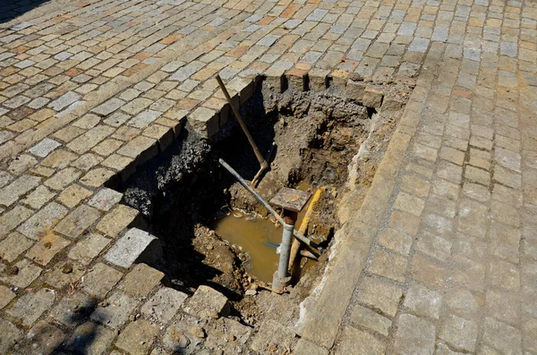 repair of the plastic supply pipe from the city water source in the cobblestone pavement. repair is difficult in a hot-water shaft, pit. the hole in the pipe is near the gas connection and cap.