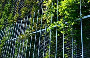 steel cladding of a building with a expanded metal lattice structure. galvanized gray nets protect the industrial building. Blue sky in contrast to a silver background, terrace, pergola