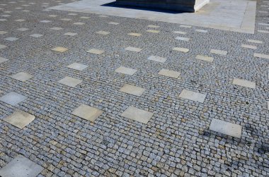 granite cobblestone tiles in a large area and inside cut irregularly placed cut stone slabs, stone tiles squares in a finer paving of granite mosaic cubes in an irregular dispersion contrasting size