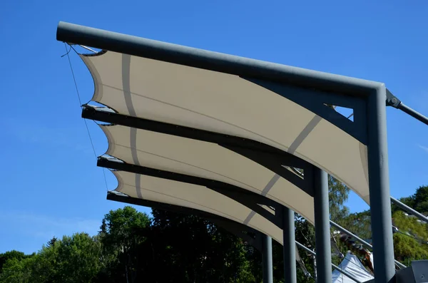 white canvas stretched, shading from the sun and rain over the terrace of the restaurant, on the playground in the kindergarten, on the platform of the promenade. pergola with metallic gray beams