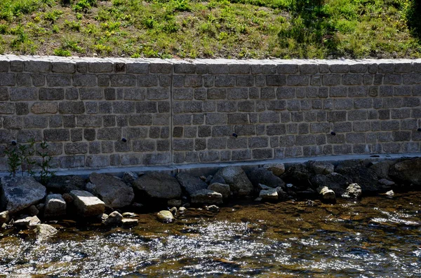 restoration of the retaining wall directly above the mountain stream. stones. the water-soaked wall needed to be repaired and the joints filled with cement mortar. mountain stream with round stones