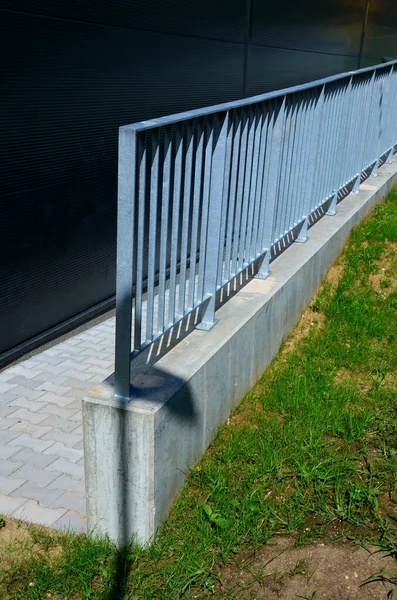 galvanized metal railings at a gray sheet metal industrial hall. concrete gray railing at the ramp. lawn around the building. concrete subfloor