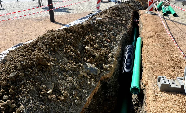 Yüksek voltajlı kablolar döşemek. Çevre elektrik direklerine zarar vermez. Siyah plastik kaplı, güçlü kablolarla kaplı bir kazı metresi. Elektrik şoku riski, telefon, açık hava, çimenlik