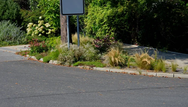 Süslü çiçek tarhı. Gri granitten yapılmış taşlar, şehir bahçesinde saman taşları, çayırlar, süs otları, havuzun kenarında çimenlik çakıl taşları.