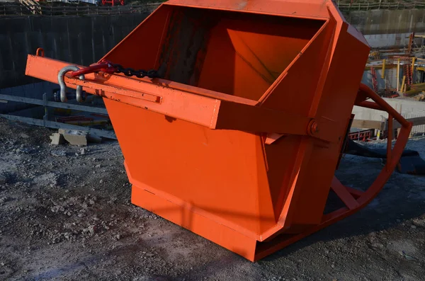 hopper used on construction sites. it is hung on a crane and then concrete is poured into it from a concrete mixer. orange tin box with bottom opening and sleeve for precise application