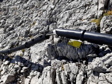 Yüksek voltaj kablosu kireç taşına bağlı, sivri uçlu kıskaçlarla. Plastik kaplama kar ve buzdan hasara karşı korur. Şimşek sembollü sarı uyarı işareti