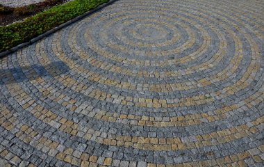 Meydanda katlanmış taşlar, gri granit kaldırımın ortasında daha büyük bir fayansla daireler çiziyor. Suyun üzerindeki daireler kaldırımın simgesidir. Büyük ve küçük harmanlanmış.